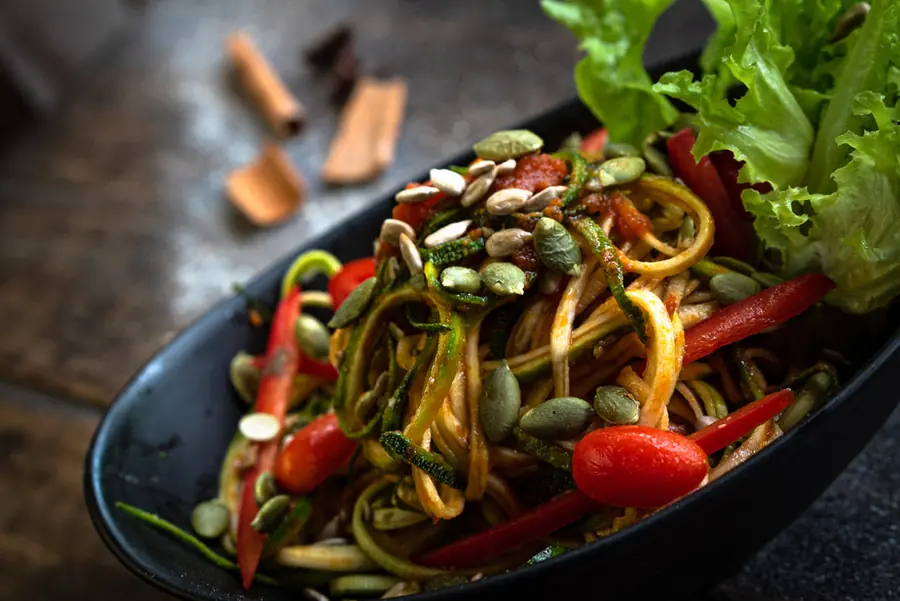 Zucchini noodle salad with cherry tomatoes, seeds and fresh lettuce.