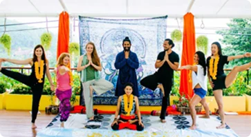 Aerial yoga class with orange hammocks and students in poses around a seated teacher