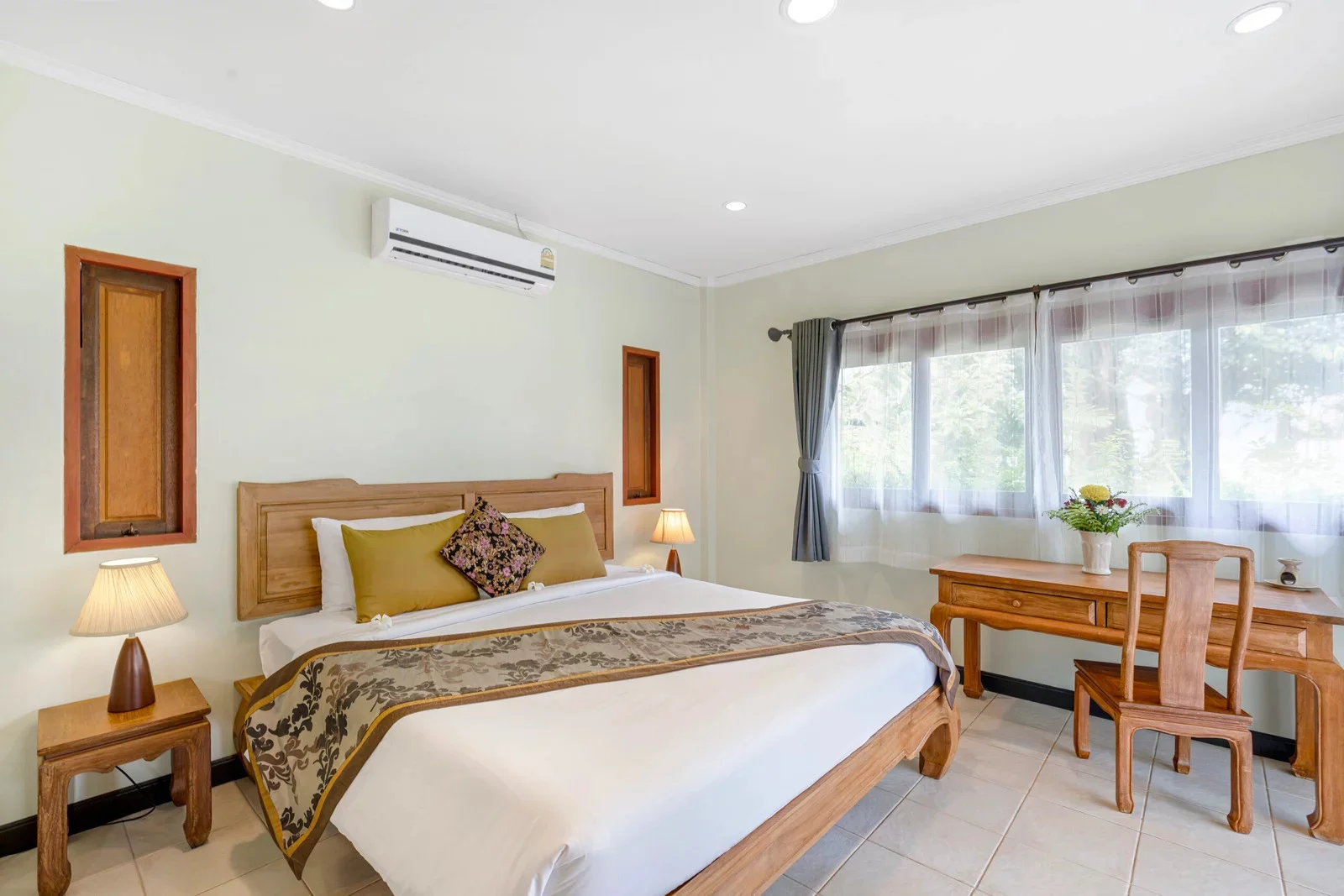 Superior room with a carved wood bed, writing desk and garden-facing windows.